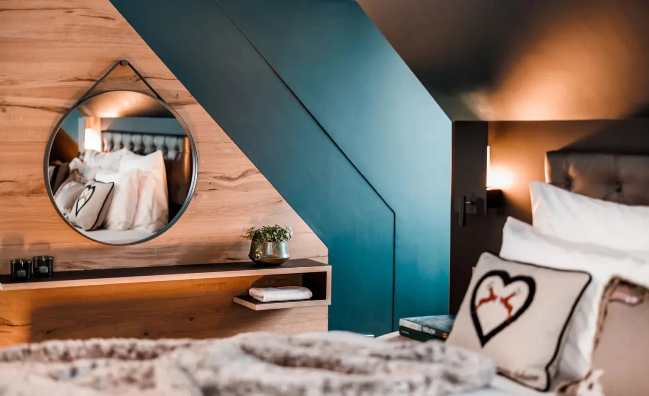 Suite im Schlosshotel Kitzbühel mit Holzwand, rundem Spiegel und Kissen mit Herzmotiv