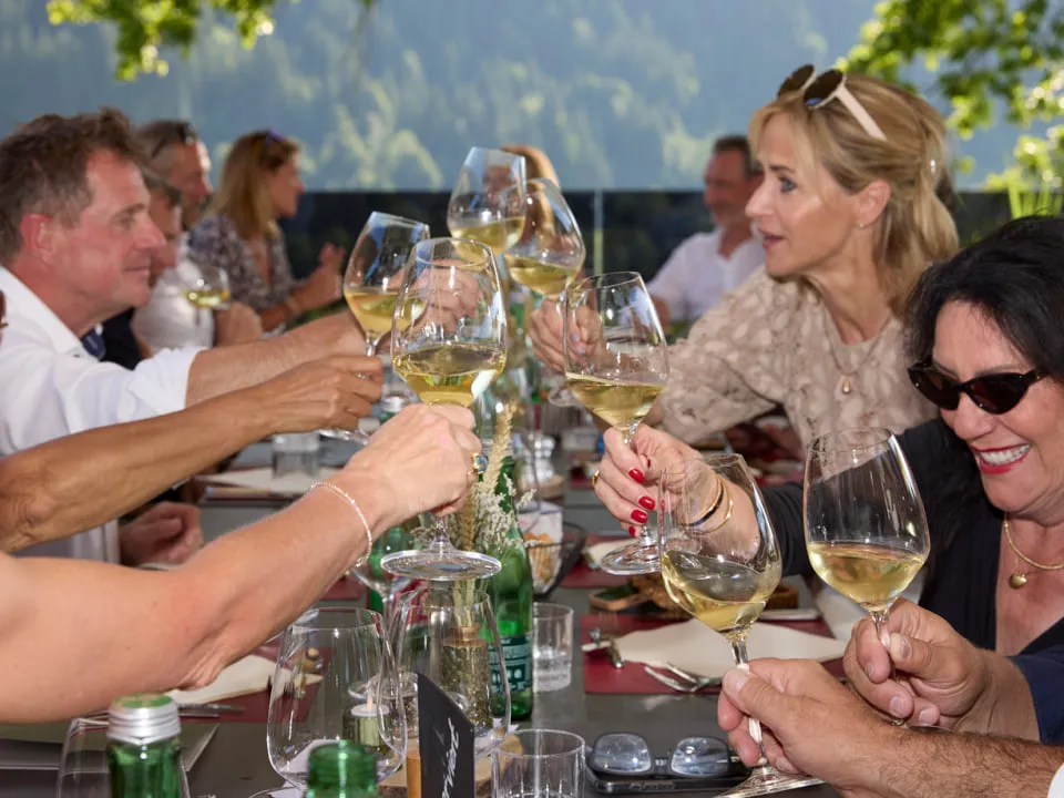 Turniergäste stoßen an einer gedeckten Tafel mit Weißwein an